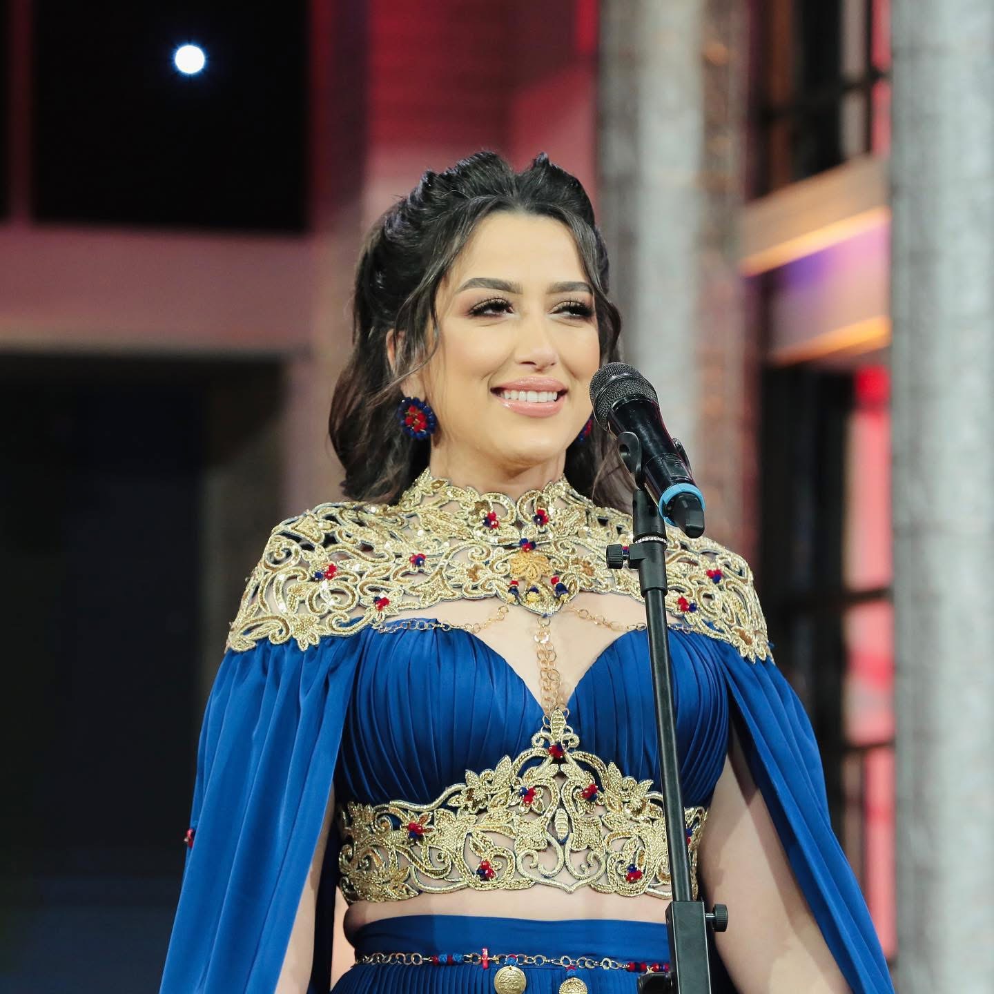 Mariem Noureddine au microphone, costume bleu et or